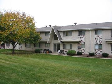 Waukesha apartment for rent - A tree with yellow leaves is in front of a grey building.