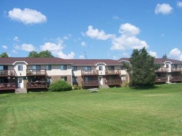 Saukville apartment for rent - an apartment building with a green lawn and a bench