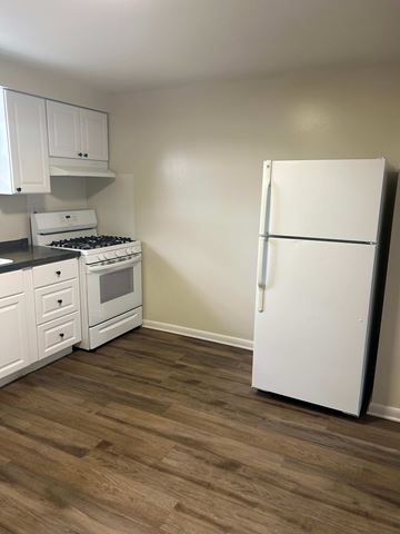 Hamburg apartment for rent - A kitchen with a white fridge, stove and cabinets.