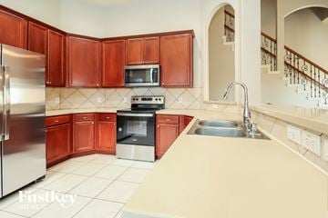 Humble house for rent - a kitchen with wooden cabinets and stainless steel appliances