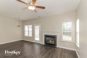 Charlotte house for rent - A spacious room with a fireplace and a ceiling fan.