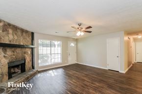 Marietta house for rent - an empty living room with a fireplace and a ceiling fan