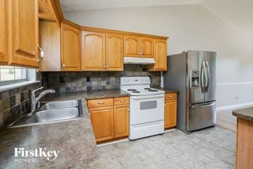 Flowery Branch house for rent - a kitchen with white appliances and wooden cabinets and stainless steel appliances