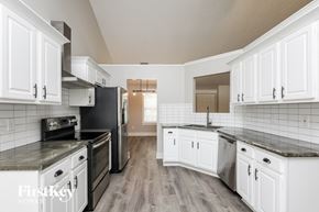Flowery Branch house for rent - a kitchen with white cabinets and a black stove and refrigerator