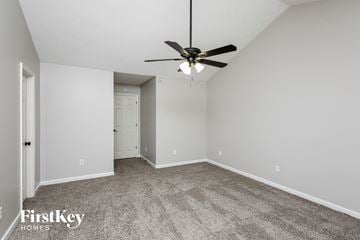 Flowery Branch house for rent - a spacious living room with carpet and a ceiling fan