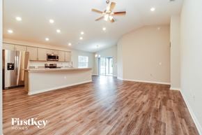 Zephyrhills house for rent - a spacious living room with a kitchen and a ceiling fan