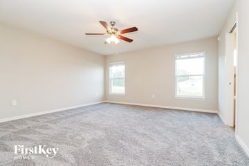 Zephyrhills house for rent - a spacious living room with carpet and a ceiling fan