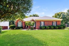 Concord house for rent - a red brick house with a green lawn and a tree
