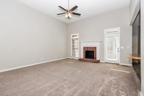 Concord house for rent - an empty living room with a fireplace and a ceiling fan