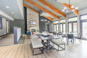 Clifton Park apartment for rent - a clubhouse with a stone fireplace and tables and chairs