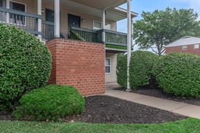 Troy apartment for rent - a brick pathway in front of a building with shrubs and trees