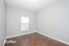 Orlando house for rent - a bedroom with white walls and wood flooring and a window
