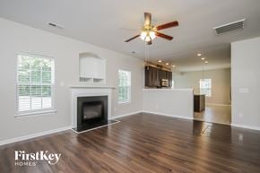 Greensboro house for rent - an empty living room with a fireplace and a ceiling fan