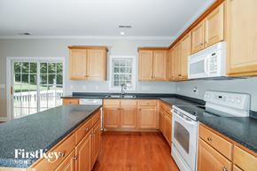 Colfax house for rent - a kitchen with wooden cabinets and black counter tops