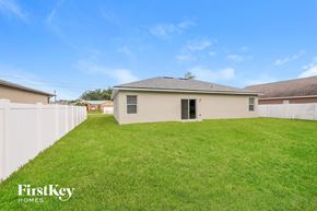Poinciana house for rent - A house with a white fence and a grassy yard.