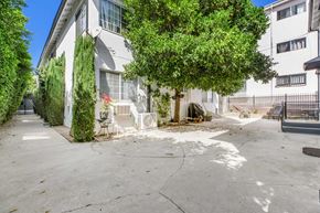 West Hollywood apartment for rent - A tree in front of a white building with a fence.
