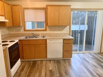 Kelso apartment for rent - A kitchen with wooden cabinets and a white dishwasher.