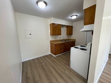 Kelso apartment for rent - A small kitchen with a white dishwasher and wooden cabinets.