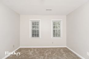 Greensboro house for rent - a bedroom with two windows and a carpeted floor