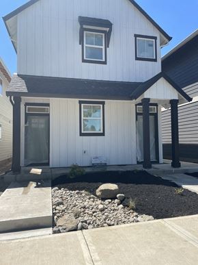 Forest Grove house for rent - A white house with a black roof and a small garden in front.