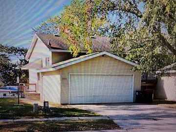 Rochester apartment for rent - A house with a white garage door and a tree in front.