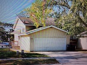 Rochester apartment for rent - A house with a white garage door and a tree in front.