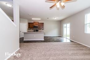 Jacksonville house for rent - an empty living room with a kitchen and a ceiling fan