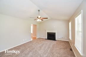 Dallas house for rent - an empty living room with a fireplace and a ceiling fan