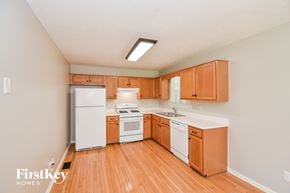 Dallas house for rent - a kitchen with wood flooring and white appliances and wooden cabinets