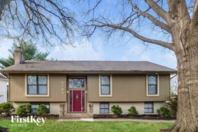 Kansas City house for rent - A beige house with a red door and a tree in front.