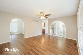 Kansas City house for rent - A spacious room with wooden floors and a ceiling fan.