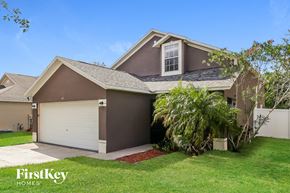 Haines City house for rent - a brown house with a garage door and a lawn