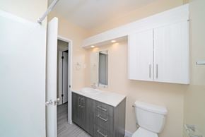 Winnipeg apartment for rent - A bathroom with a toilet, sink, and cabinets.
