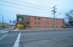 Winnipeg apartment for rent - A red brick building with a green sign on the left side.