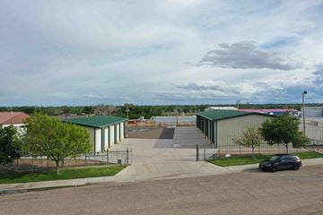Pueblo apartment for rent - A parking lot with a few cars and a building in the background.
