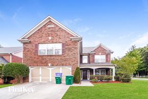 Snellville house for rent - A brick house with a garage and two trash bins in front.