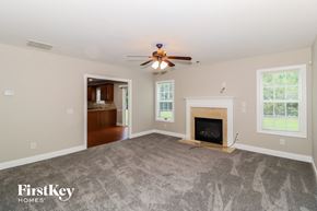 Snellville house for rent - A spacious living room with a fireplace and a ceiling fan.