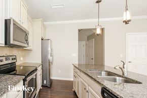 Statesville house for rent - a kitchen with white cabinets and granite counter tops