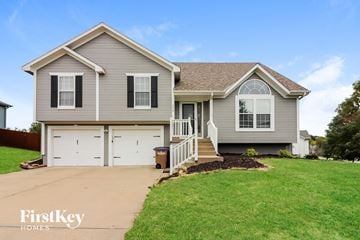 Raymore house for rent - a gray house with a lawn and a driveway
