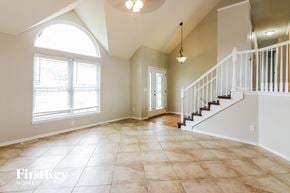 Raymore house for rent - an empty living room with a staircase and a large window