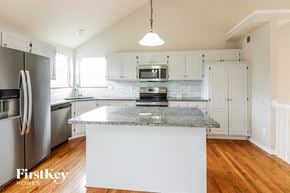 Raymore house for rent - a renovated kitchen with white cabinets and granite counter tops