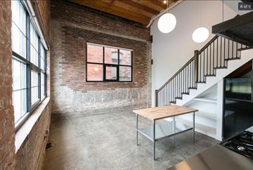 Detroit apartment for rent - a living room with a table and a brick wall