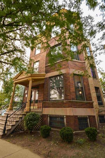 Chicago apartment for rent - an old brick building with a porch and a tree