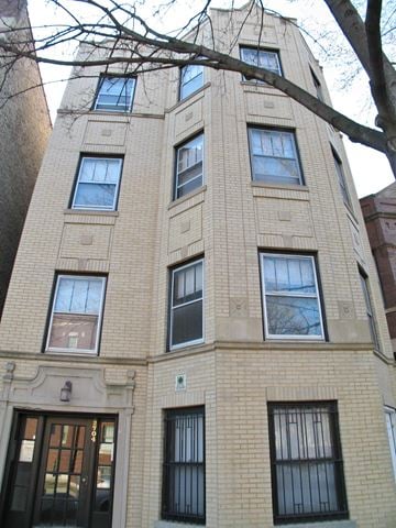 Chicago apartment for rent - a tall brick building with many windows and a tree