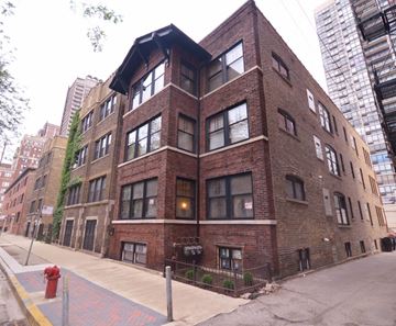Chicago apartment for rent - a red brick building on a city street with tall buildings