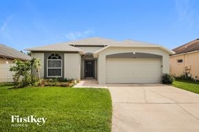 Orlando house for rent - a beige house with a garage door and a lawn