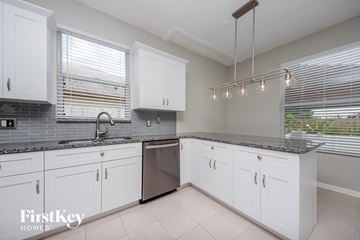 Orlando house for rent - a white kitchen with white cabinets and stainless steel appliances