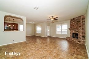 Cibolo house for rent - an empty living room with a brick fireplace and tile flooring
