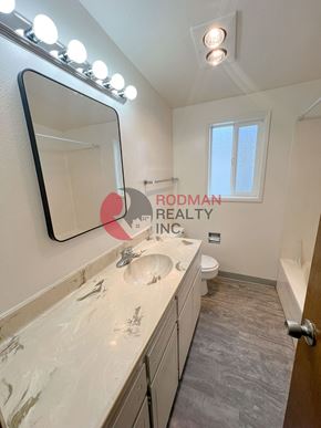 Longview apartment for rent - A bathroom with a mirror, sink, toilet, and a window.