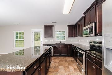 Whitsett house for rent - a kitchen with dark wood cabinets and granite counter tops and white appliances